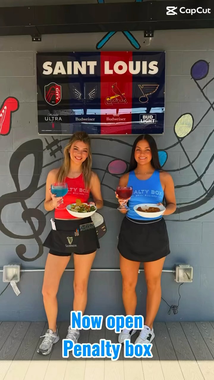 Penalty Box servers holding signature cocktails and dishes in front of the Saint Louis sports mural
